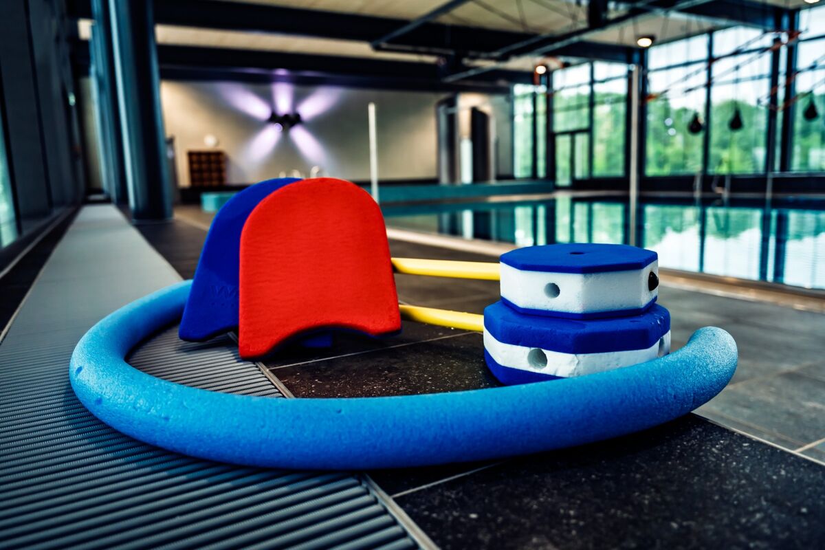 Zu sehen sind farbige Schwimmnudeln, Schwimmbretter und Schwimmsprosse auf dem Boden vor dem neuen 25 m - 4 Bahnen - Becken liegend.