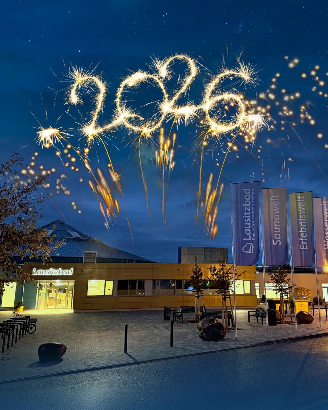 Die Außenansicht des beleuchteten Lausitzbades am Abend mit dem leuchtenden Schriftzug 2026 darüber